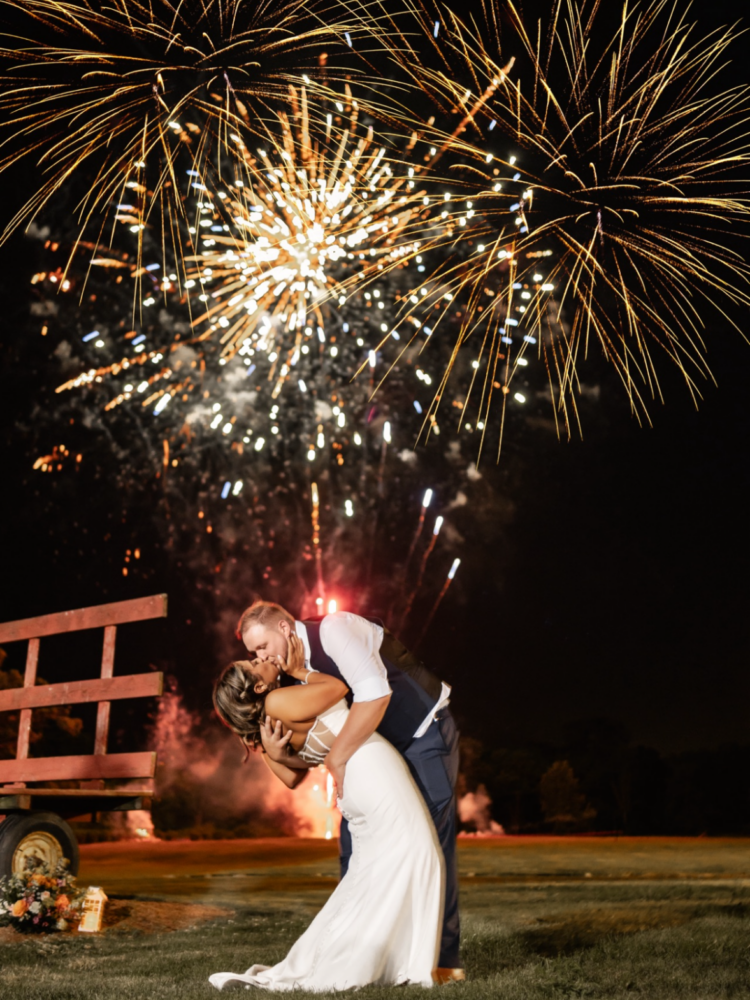 bride and groom kissing under fireworks